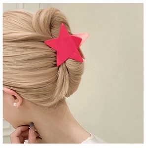 Detail of a large magenta star-shaped hair claw clip styled on a golden brown updo hairstyle