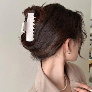 Close-up of a large pink hair claw clip on model's hair with elegant accessories