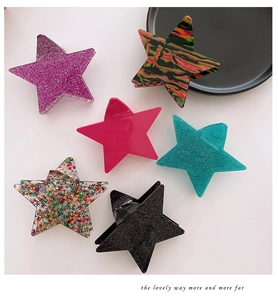 Flat lay of six large star-shaped hair claws with glitter and artistic patterns