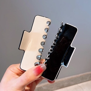 Minimalist large shark hair claw clips in beige and black colors shown in hand