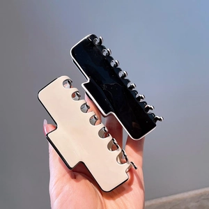 Close-up of black and cream minimalist hair claws with glossy resin finish for women