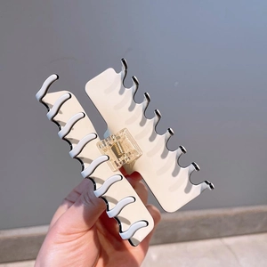 Detail view of a large white hair claw clip with stylish black and white wavy edge design