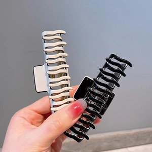 Close-up of black and cream large wave hair claws with glossy finish for daily styling