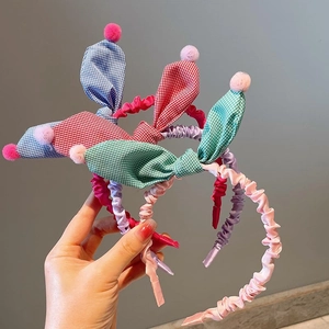 Detailed view of three checkered rabbit ear headbands with soft plush pom poms for kids