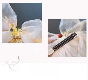 Detail einer weißen Organza-Haarschleife mit Zitronenstickerei und Metall-Haarspange