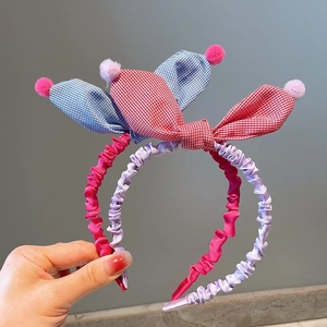 Detail of Korean style pleated fabric headbands with cute rabbit ears and plush pom-poms