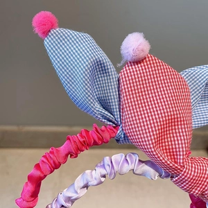 Detail of plaid bunny ears headbands with soft pom-poms and pleated satin fabric