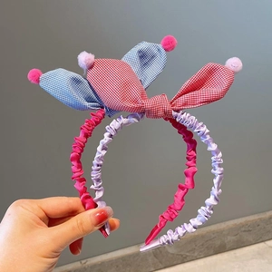 Detail view of plaid pleated headbands with decorative pom-poms for children accessories