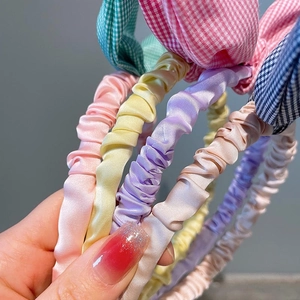 Detailed close-up of pleated fabric headbands in assorted macaron colors and plaid patterns