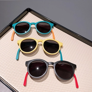 Three pairs of colorful round-frame foldable kids sunglasses on a textured tray