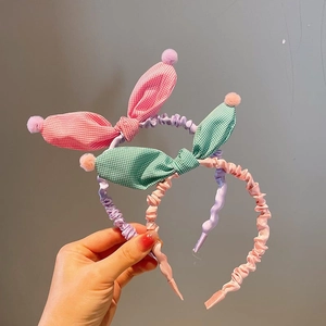 Detail of plaid rabbit ear headbands with soft pom-poms and pleated fabric cover