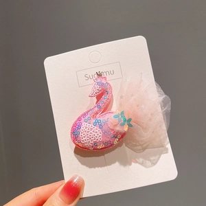 Détail de la pince à cheveux cygne rose avec paillettes et voile en tulle sur carte