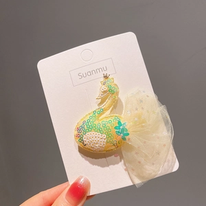 Détail de la pince à cheveux cygne en paillettes jaunes et vertes avec tulle étoilé