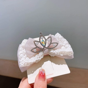 Dettaglio di fermaglio per capelli con fiocco rosa, corona di perle e gemma a cuore