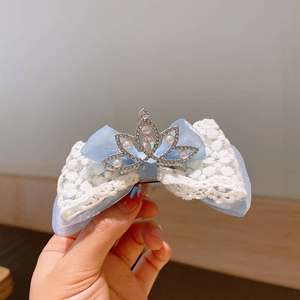 Dettaglio della molletta a fiocco in tulle blu con pizzo e corona di perle