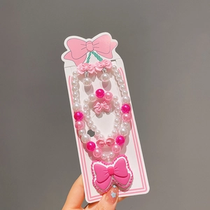 Détail d'un ensemble de bijoux rose avec nœud et perles pour filles avec collier