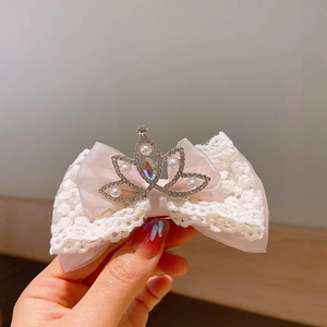 Dettaglio di un fermaglio per capelli con fiocco in pizzo, corona di perle e strass