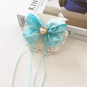 Detailed view of blue satin bow hair clip with pearl heart and lace tassel fringe
