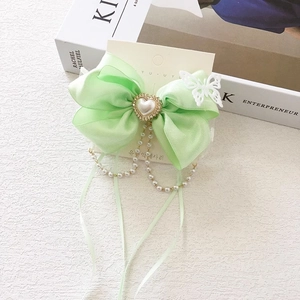Detail of light green satin bow hair clip with pearl tassels and lace butterfly accent