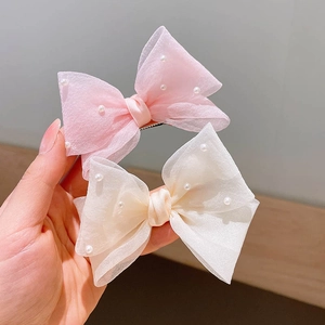 Détail de barrettes nœuds en organza rose et blanc avec perles et pinces métalliques
