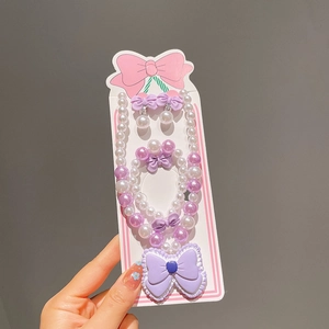 Vue détaillée d'une parure de bijoux pour enfants avec perles mauves et pendentifs nœuds