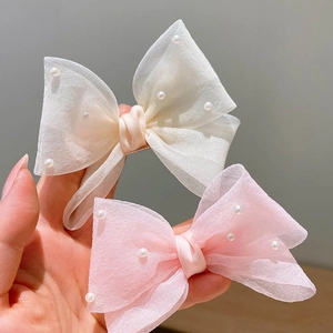 Détail des barrettes nœuds en organza blanc et rose avec perles pour petites filles