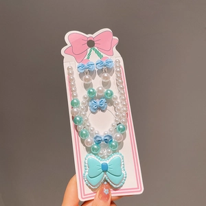 Détail d'un ensemble de bijoux pour enfants avec nœuds bleus et perles vertes