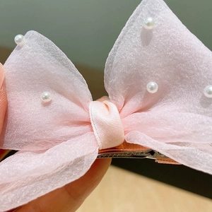 Détail de la barrette à nœud en résille rose avec perles et pince crocodile métallique