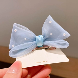 Détail d'une pince à cheveux nœud en organza bleu clair avec perles blanches