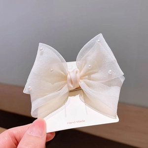 Détail d'une pince à cheveux avec nœud en organza pour filles et perles élégantes