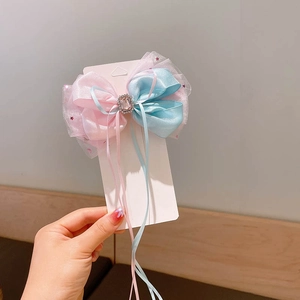 Detailed close-up of pink and blue tulle bow hair clip with a sparkling central rhinestone
