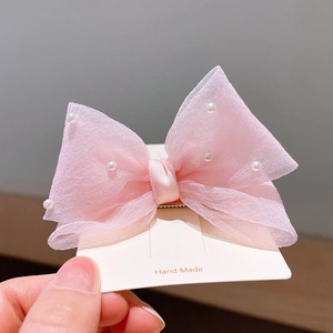 Détail de la pince à cheveux noeud en tulle rose avec ornements en perles blanches