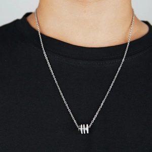 Macro shot of a silver titanium steel necklace with a minimalist cylindrical pendant