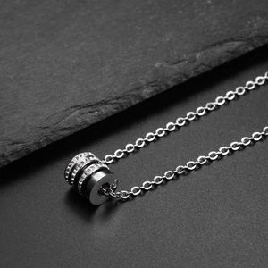 Macro shot of silver titanium cylinder pendant necklace with black enamel and zircons