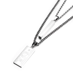 Macro detail of silver dollar sign pendant and supreme rectangle bar on cuban link chain