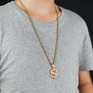 Detalle de collar hip-hop dorado con colgante de dólar brillante sobre camiseta