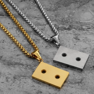 Detail of hip-hop cassette tape pendant in brushed gold and silver titanium steel
