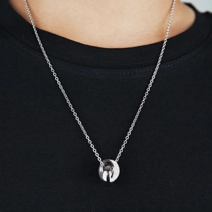 Detail of silver-toned double ring necklace with zircon pavé worn by a model