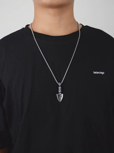 Close-up of hip-hop silver arrow pendant with cross engraving on thick twisted metal chain