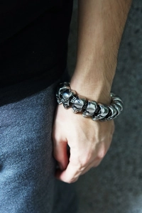 Detailed view of heavy titanium steel skull links on a rugged punk bracelet for men