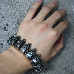 Detailed close-up of punk style stainless steel skull head bracelet worn on a male wrist