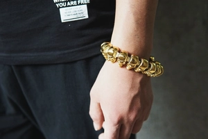 Detail of a gold hip-hop skull bracelet worn on wrist showing polished punk style