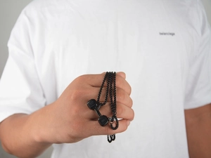 Macro shot of a matte black dumbbell pendant necklace with engraved numeric details