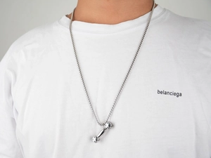 Nahaufnahme eines Hip-Hop-Hantelanhängers an einer Stahlkette auf einem weißen T-Shirt