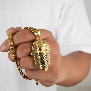 Macro detail of gold Egyptian Pharaoh pendant with sparkling crystals and thick bead chain