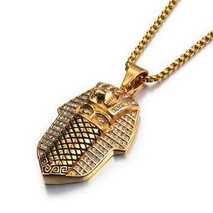 Macro detail of gold pharaoh pendant necklace with white crystals and box chain link