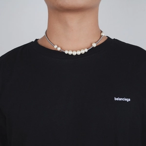 Detail of unisex pearl and silver bead necklace worn on a black crewneck shirt