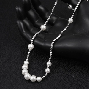 Macro detail of gradient pearl necklace with silver steel beads on black display