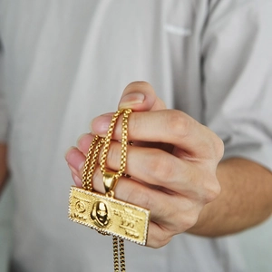 Macro-opname van hiphop-dollarpendant met kristallen rand aan een gouden bolletjesketting