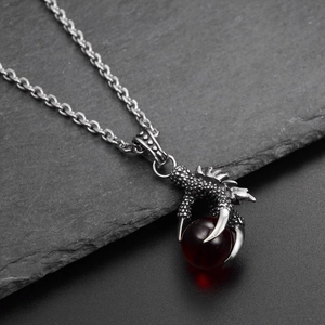 Primer plano detallado del colgante garra de dragón con gema roja oscura y cadena de plata